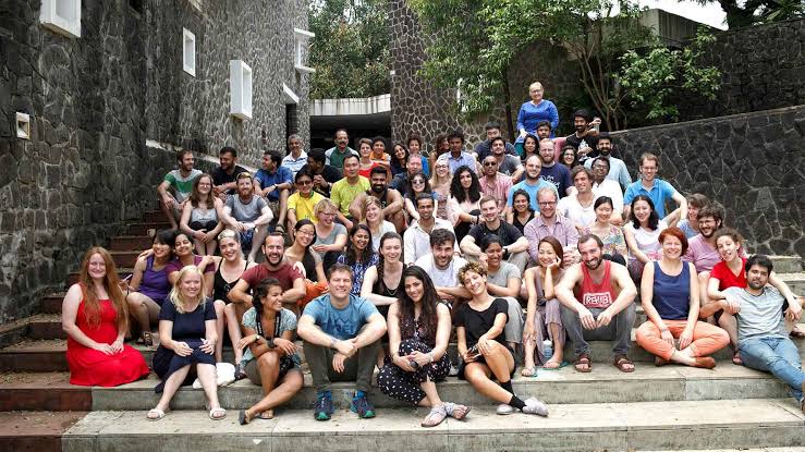 A group gathered on outdoor stone steps among the college buildings